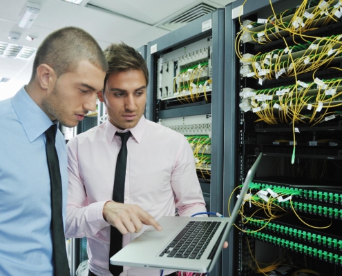Tech professionals looking at laptop while working on network system