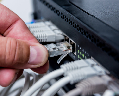 Technician connecting network cables to switches. Connecting cables in server cabinet