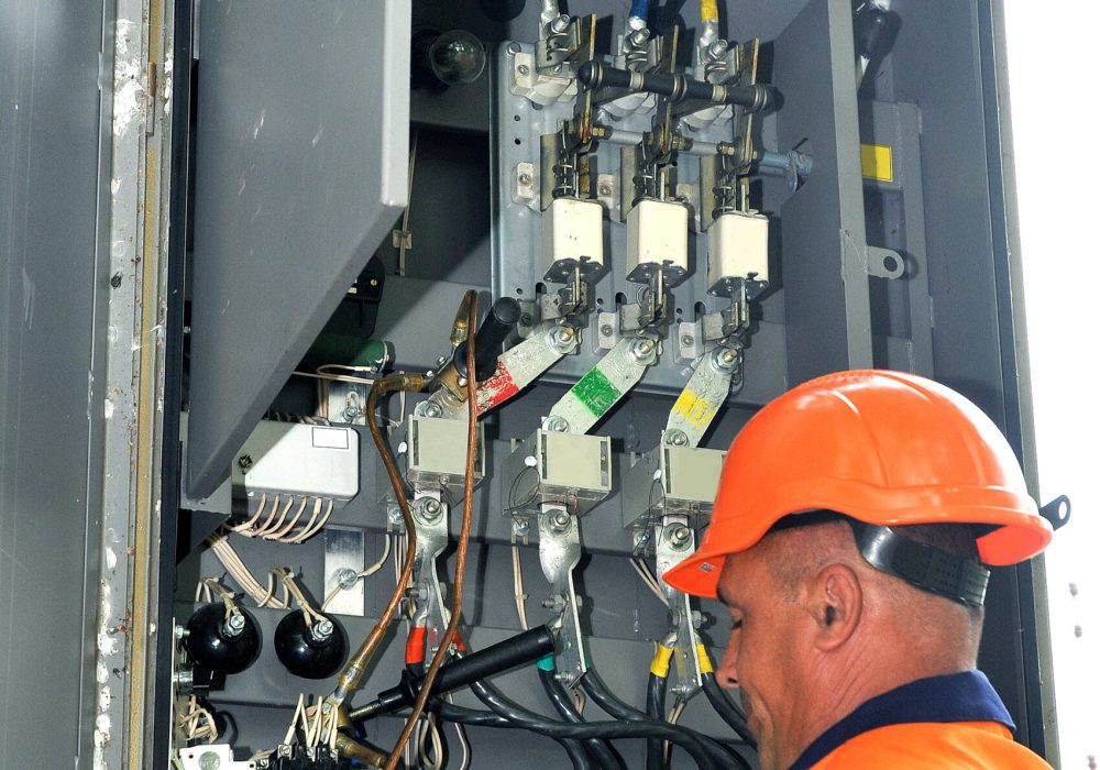 Electrical engineer measures the voltage in an electrical control cabinet